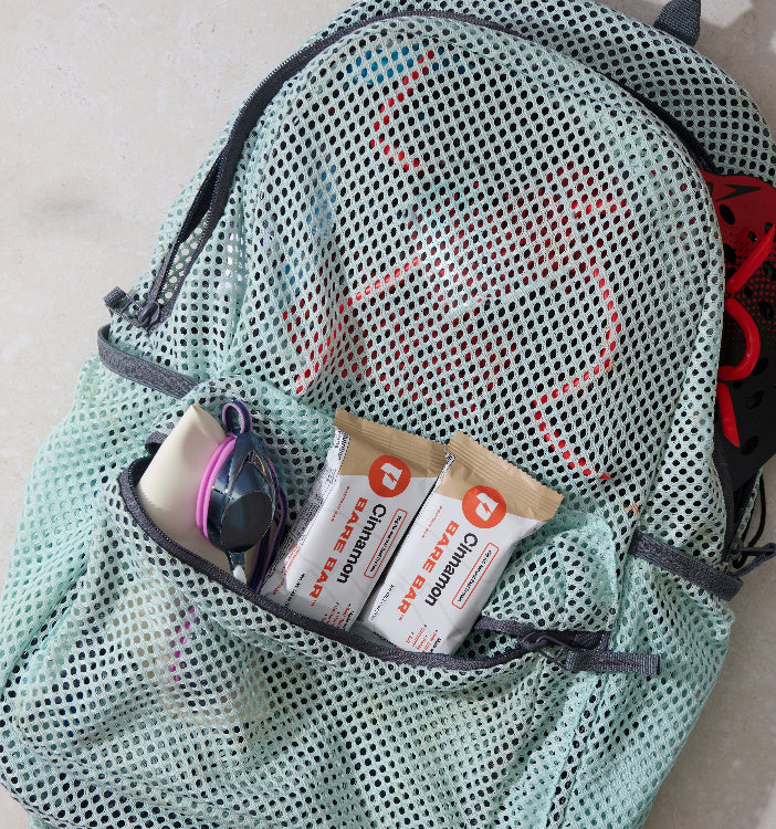 Bare Bars in a Mesh bag with sunglasses and toiletries on a light background